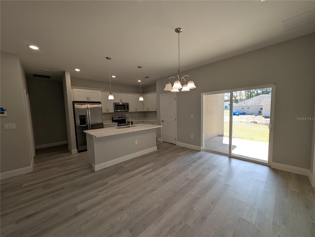 kitchen featuring sink, pendant lighting, stainless steel appliances, a kitchen island with sink, and white cabinets