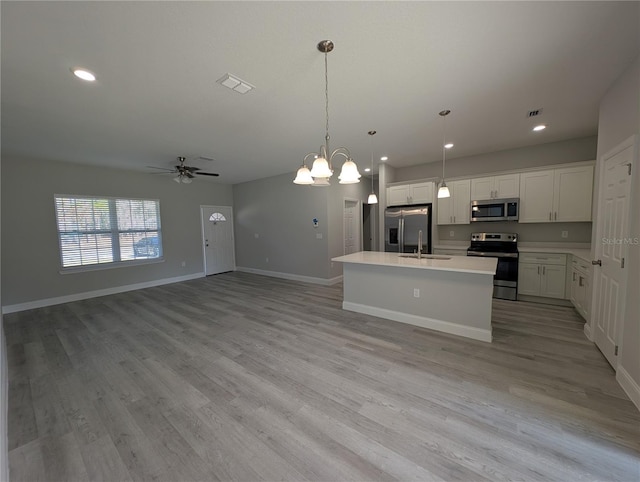 kitchen featuring pendant lighting, sink, white cabinetry, a kitchen island with sink, and stainless steel appliances