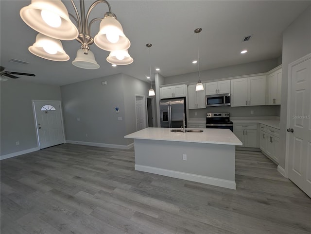 kitchen with pendant lighting, an island with sink, white cabinets, and appliances with stainless steel finishes