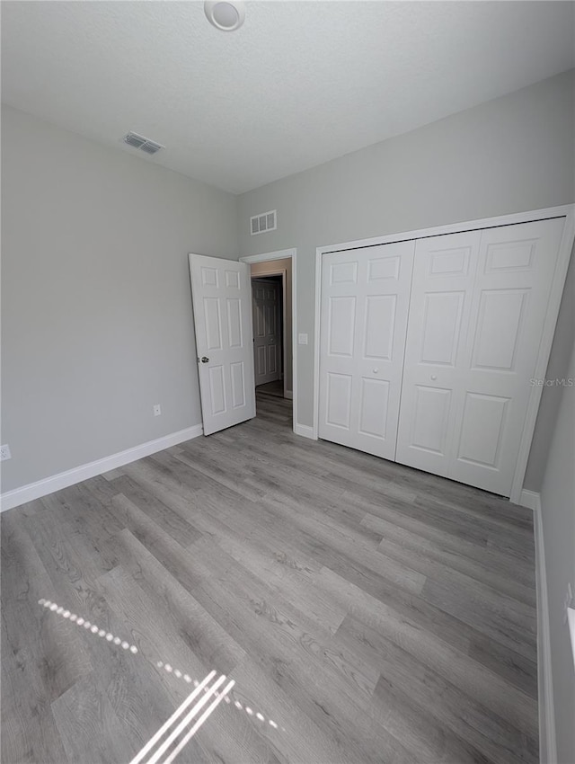 unfurnished bedroom with light wood-type flooring and a closet