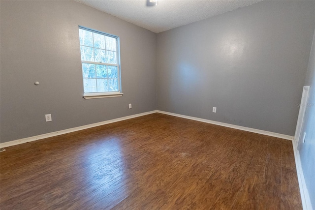 spare room featuring dark hardwood / wood-style floors and a textured ceiling