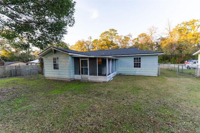 rear view of house with a yard and a sunroom