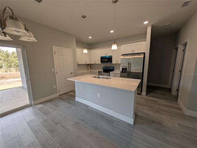 kitchen featuring appliances with stainless steel finishes, pendant lighting, sink, white cabinets, and a center island with sink