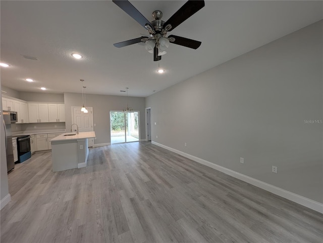 kitchen featuring appliances with stainless steel finishes, pendant lighting, sink, white cabinets, and a kitchen island with sink