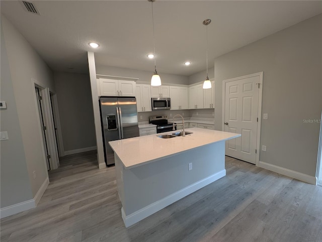 kitchen featuring sink, white cabinetry, hanging light fixtures, stainless steel appliances, and light hardwood / wood-style floors