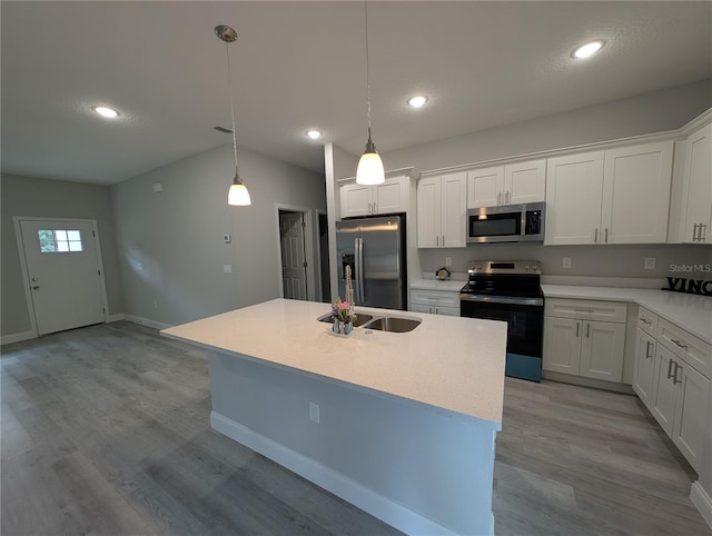 kitchen with hanging light fixtures, white cabinetry, appliances with stainless steel finishes, and an island with sink