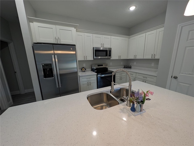 kitchen with light stone counters, sink, stainless steel appliances, and white cabinets