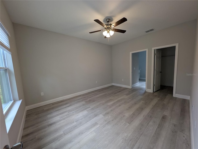 unfurnished bedroom with a closet, ceiling fan, light hardwood / wood-style floors, and multiple windows