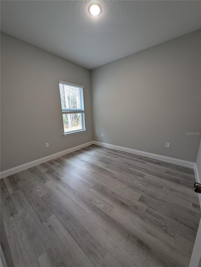 empty room with a textured ceiling and light wood-type flooring