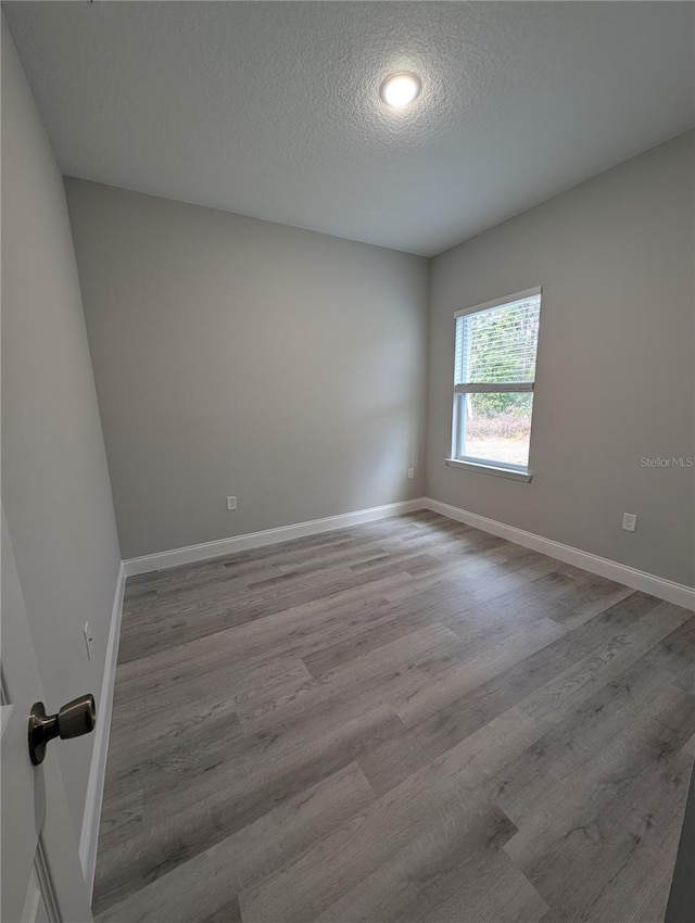 empty room with light hardwood / wood-style flooring and a textured ceiling