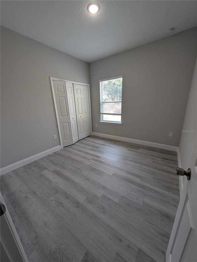 unfurnished bedroom featuring light hardwood / wood-style floors, a closet, and a textured ceiling