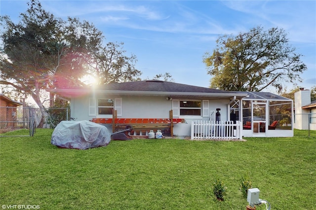 back of house with a lanai and a lawn