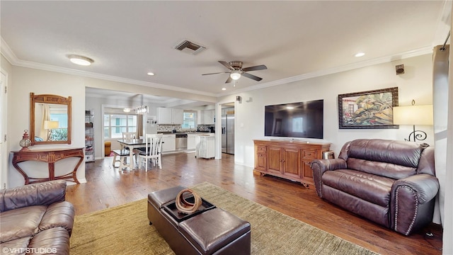 living room featuring hardwood / wood-style flooring, ornamental molding, and ceiling fan