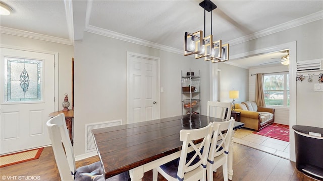 dining space with ceiling fan with notable chandelier, ornamental molding, and hardwood / wood-style floors