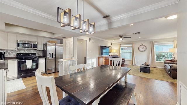 dining space featuring ceiling fan, light wood-style flooring, visible vents, baseboards, and ornamental molding