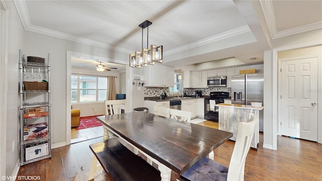 dining room featuring light wood-style flooring, ornamental molding, and baseboards