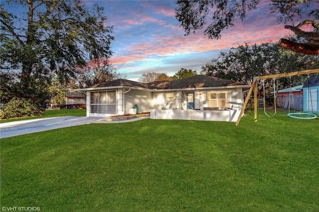 view of front of home featuring a lawn, concrete driveway, a playground, and fence