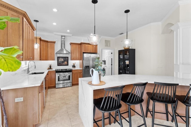 kitchen featuring pendant lighting, sink, appliances with stainless steel finishes, ornamental molding, and wall chimney exhaust hood