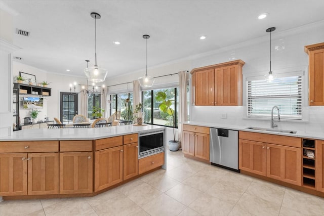 kitchen with hanging light fixtures, ornamental molding, appliances with stainless steel finishes, and sink