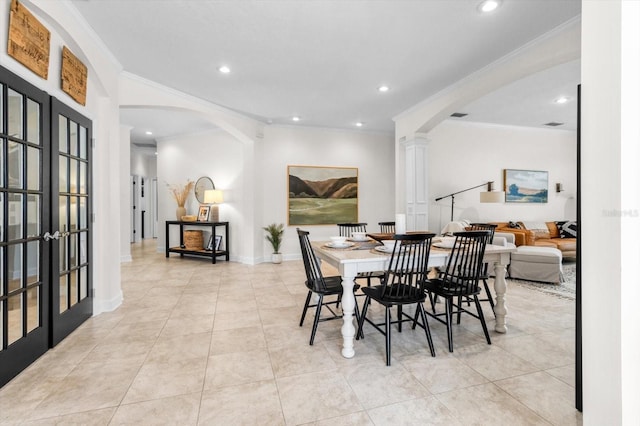 tiled dining area with decorative columns, crown molding, and french doors