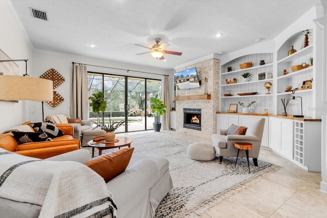 tiled living room featuring ornamental molding, ceiling fan, and a fireplace