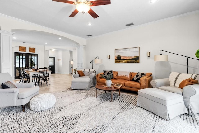 living room featuring decorative columns, ornamental molding, and ceiling fan