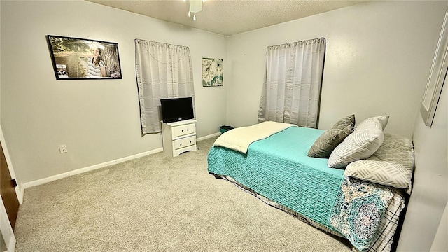 carpeted bedroom featuring ceiling fan and a textured ceiling