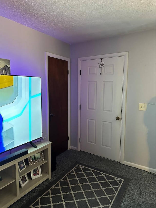 foyer with a textured ceiling and dark colored carpet