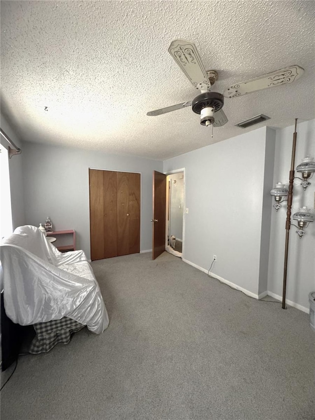 carpeted bedroom with ceiling fan, a closet, and a textured ceiling