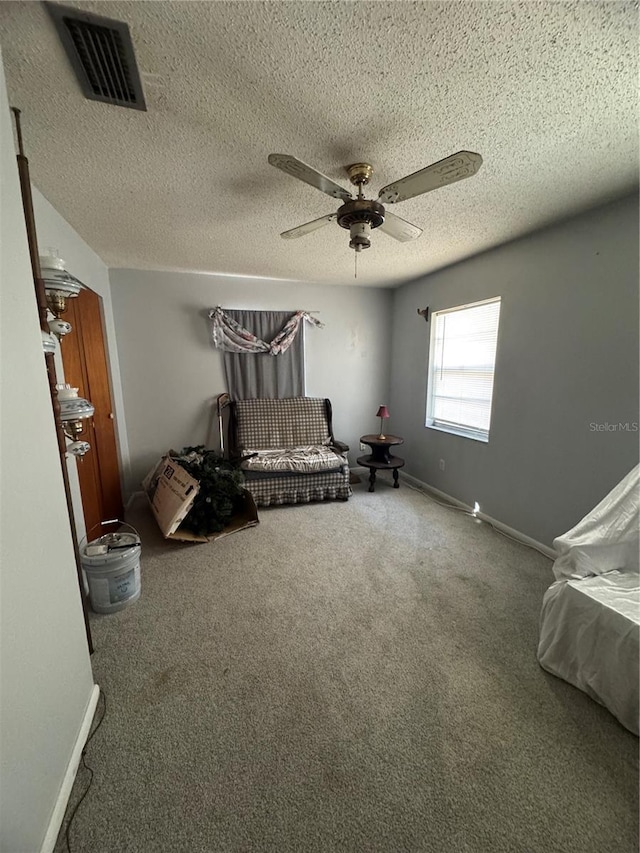 sitting room featuring ceiling fan, carpet, and a textured ceiling