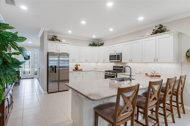 kitchen with stainless steel appliances, white cabinetry, a kitchen breakfast bar, and kitchen peninsula