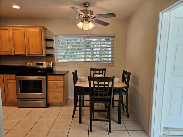 kitchen featuring tasteful backsplash, light tile patterned flooring, stainless steel range with electric cooktop, and ceiling fan