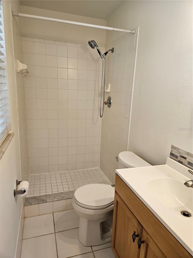 bathroom featuring a tile shower, vanity, tile patterned floors, and toilet