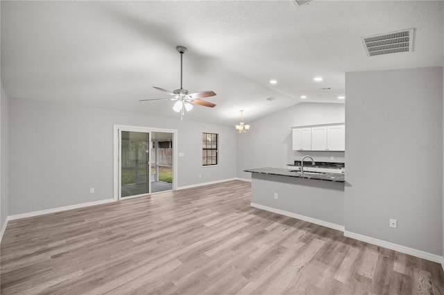 unfurnished living room featuring vaulted ceiling, sink, ceiling fan with notable chandelier, and light hardwood / wood-style flooring