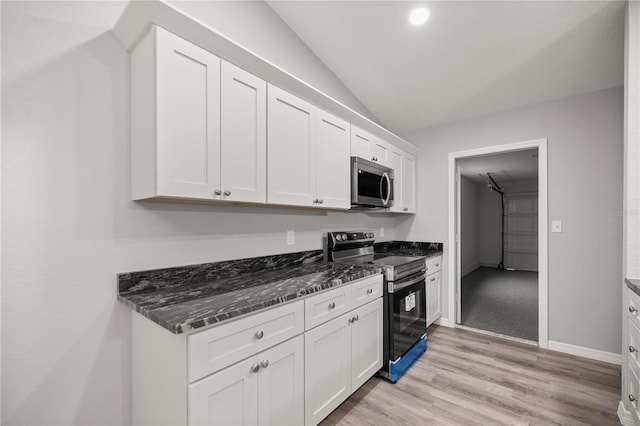 kitchen featuring white cabinetry, light wood-type flooring, dark stone countertops, and appliances with stainless steel finishes