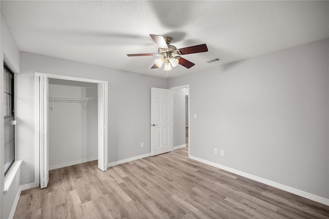 unfurnished bedroom featuring ceiling fan, a textured ceiling, light wood-type flooring, and a closet