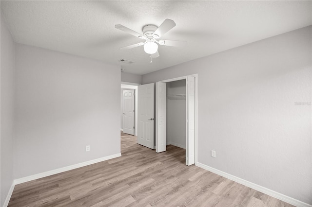 unfurnished bedroom featuring ceiling fan, a textured ceiling, light wood-type flooring, and a closet