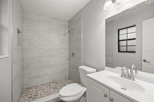 bathroom featuring tiled shower, vanity, and toilet