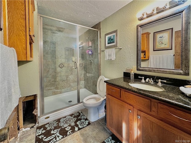 full bath with a stall shower, a textured wall, toilet, a textured ceiling, and vanity