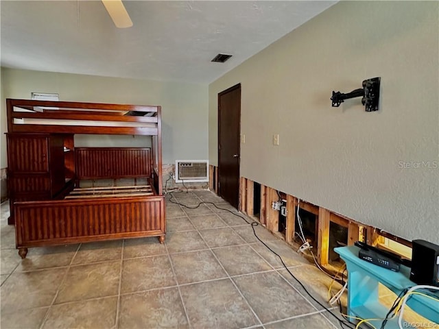 interior space featuring a wall mounted air conditioner, tile patterned flooring, visible vents, and a ceiling fan