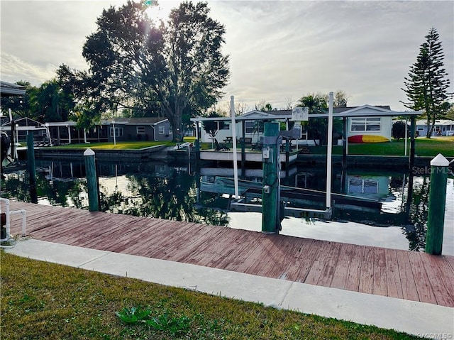 view of dock featuring a water view, boat lift, and a residential view