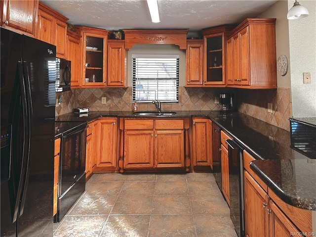 kitchen with glass insert cabinets, a sink, backsplash, and black appliances