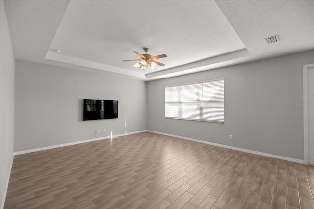 spare room with ceiling fan, wood-type flooring, a raised ceiling, and a textured ceiling