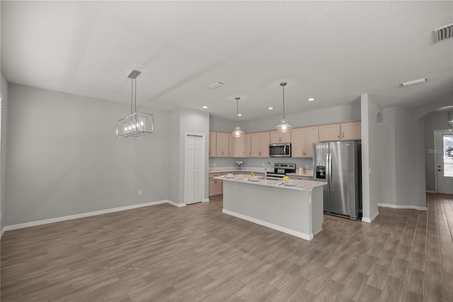 kitchen featuring light brown cabinetry, decorative light fixtures, a kitchen island with sink, and appliances with stainless steel finishes