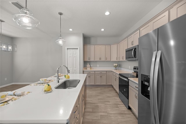 kitchen featuring sink, decorative light fixtures, a center island with sink, a textured ceiling, and appliances with stainless steel finishes