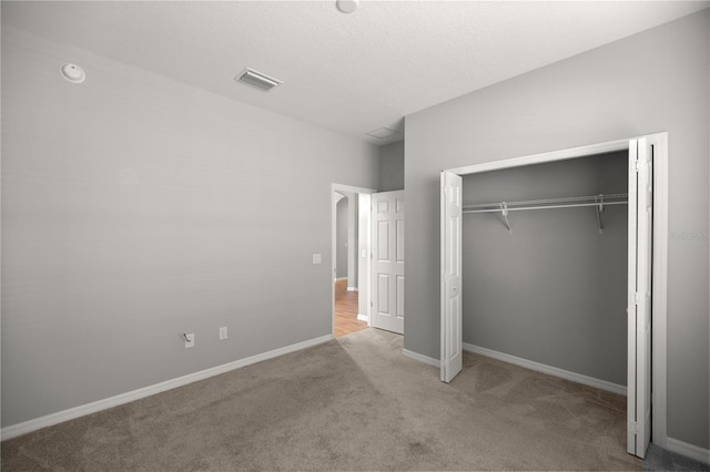 unfurnished bedroom with a closet, light carpet, and a textured ceiling