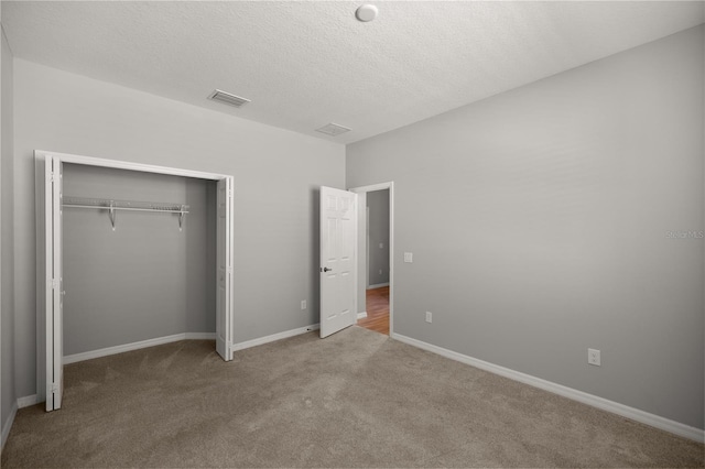 unfurnished bedroom with carpet floors, a textured ceiling, and a closet