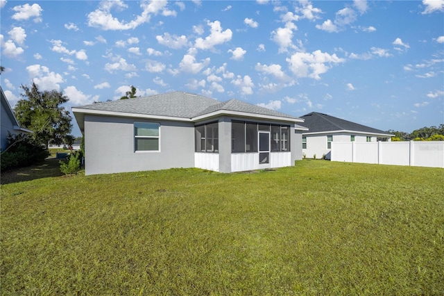 rear view of property with a sunroom and a yard