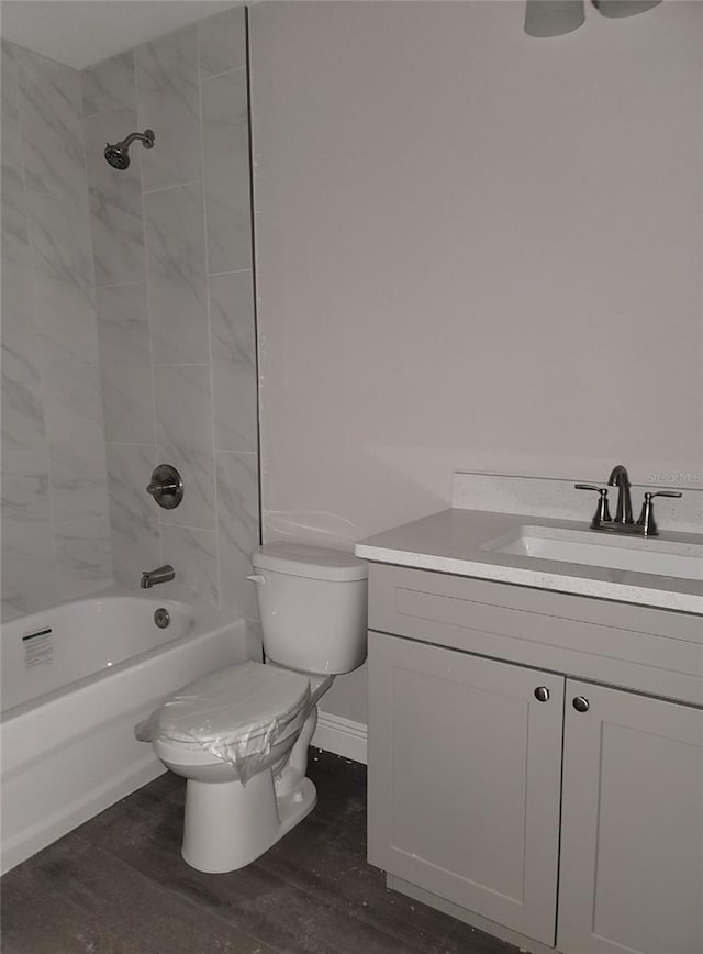 full bathroom featuring vanity, tiled shower / bath, wood-type flooring, and toilet