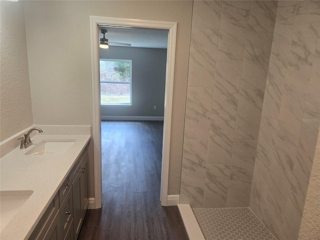 bathroom featuring a tile shower, vanity, hardwood / wood-style floors, and ceiling fan